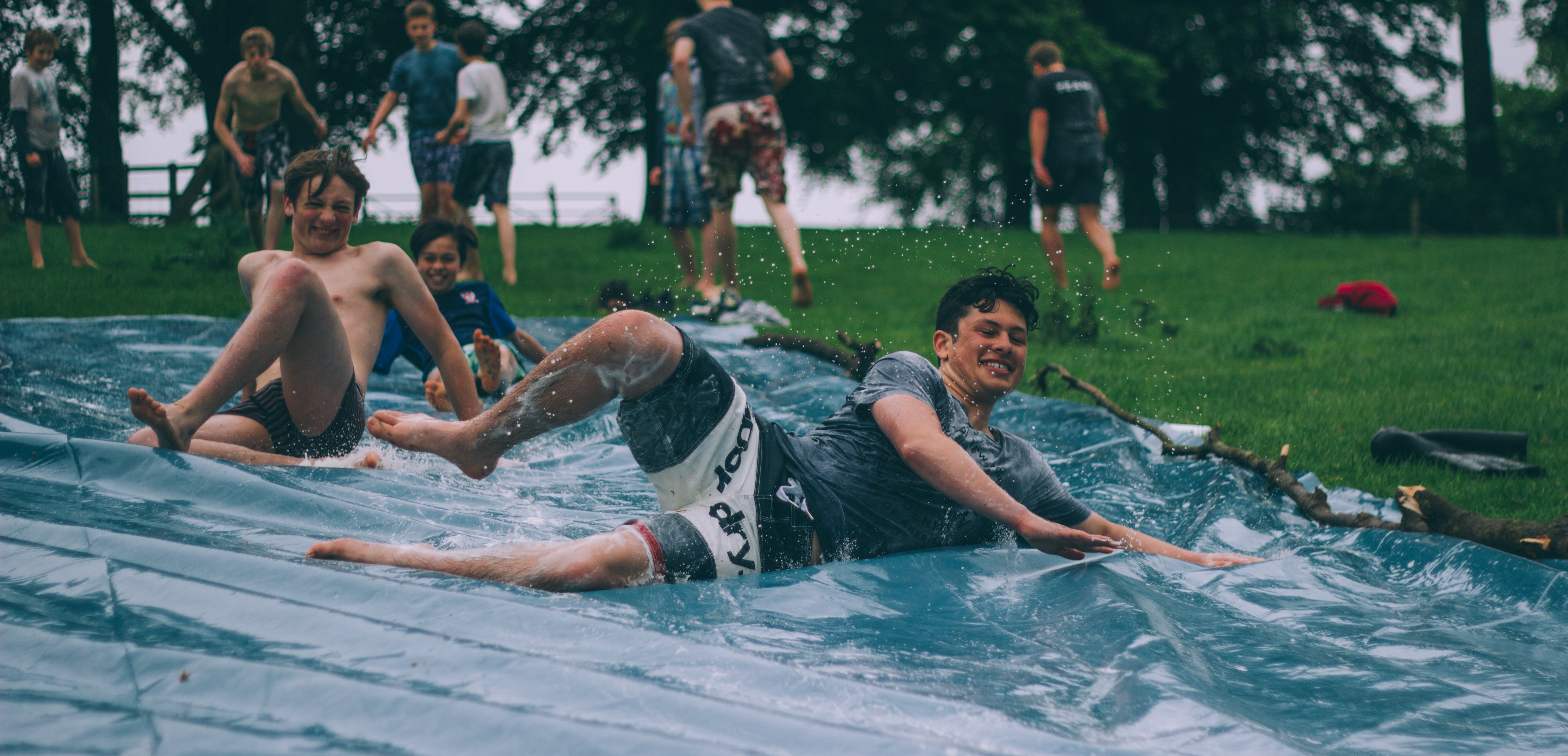 Teenage boys on a water slide looking happy