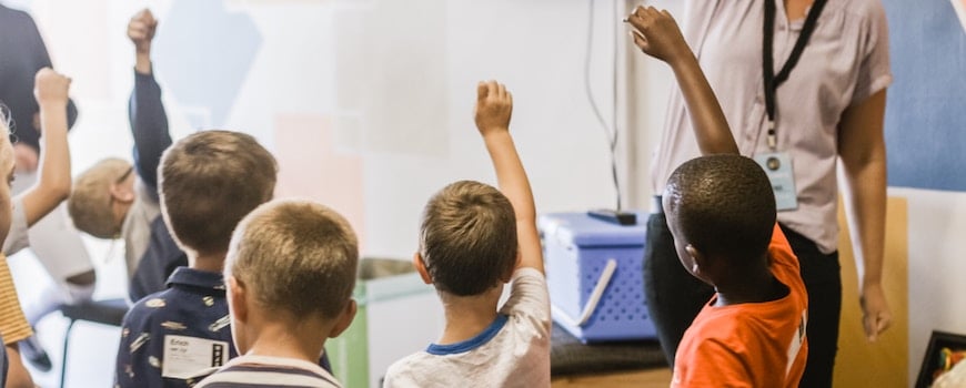 Prep School children holding up their hands in class